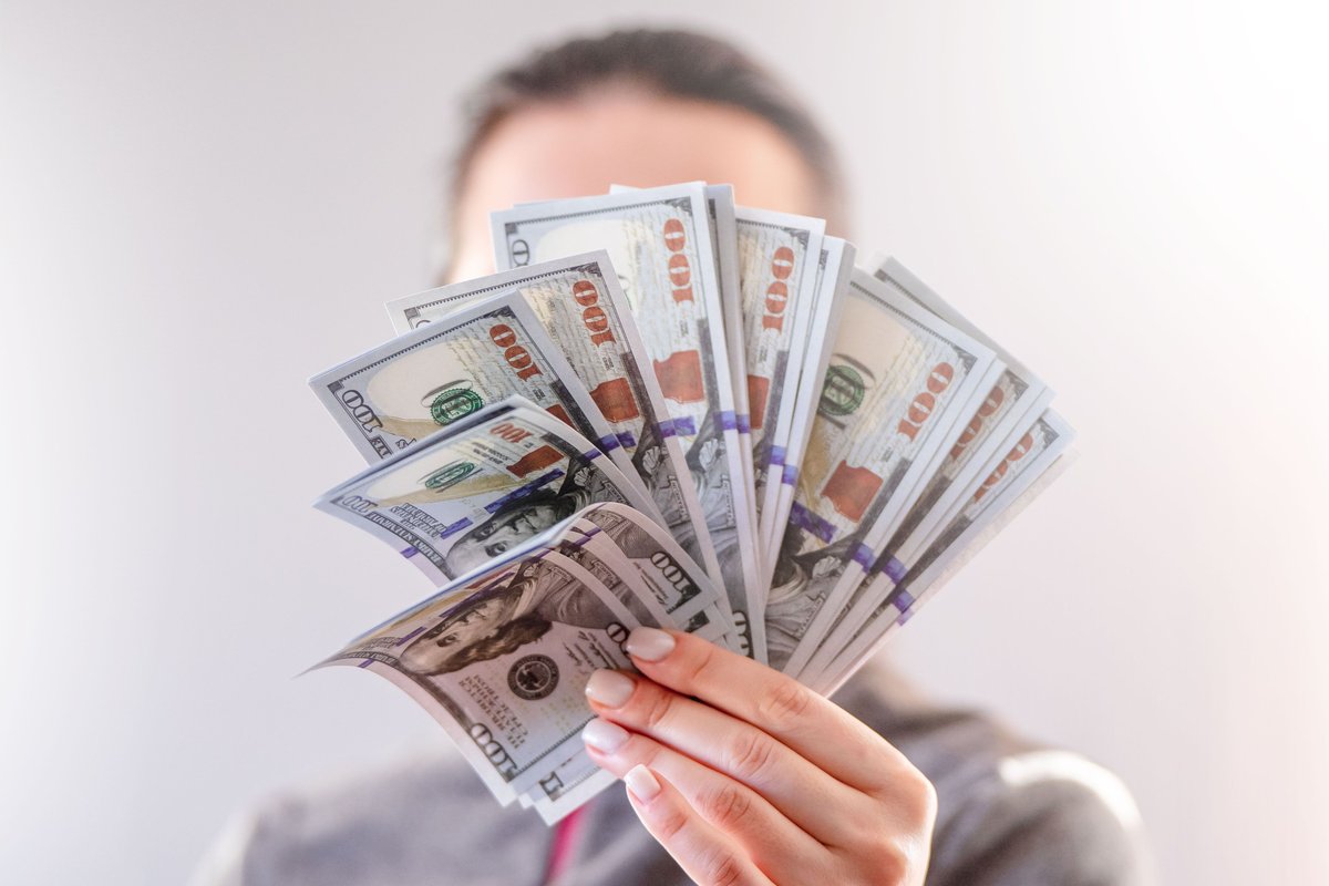 A person holding a fan of US dollar bills